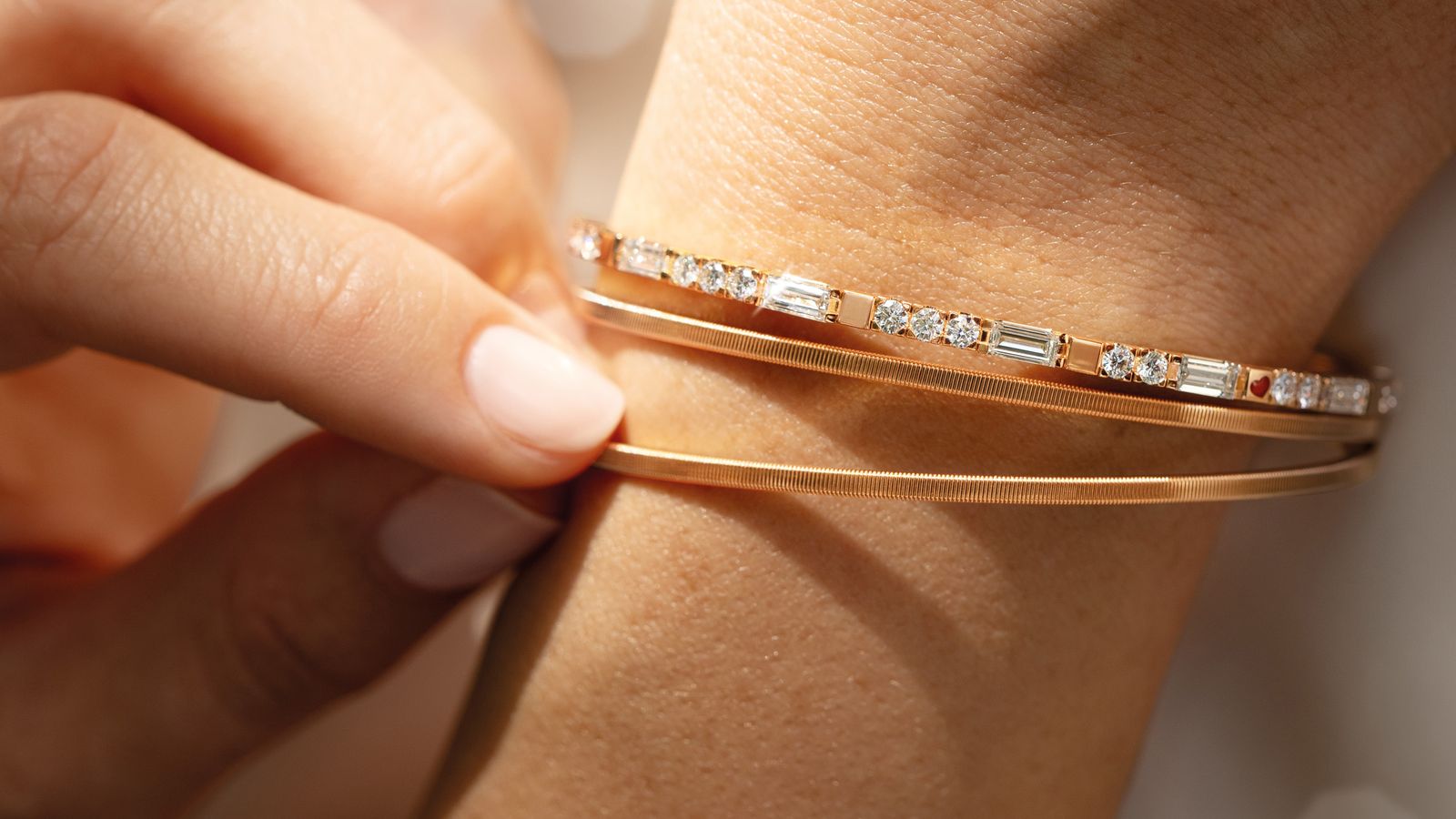 Das Armband UMARME MICH. Baguette-Zauber aus federndem 18-Karat Gelbgold, gepaart mit handgefassten Baguette-Diamanten und einem tiefroten Herz.