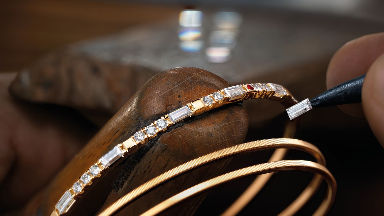 Das Armband UMARME MICH. Baguette-Zauber aus federndem 18-Karat Gelbgold, gepaart mit handgefassten Baguette-Diamanten und einem tiefroten Herz.