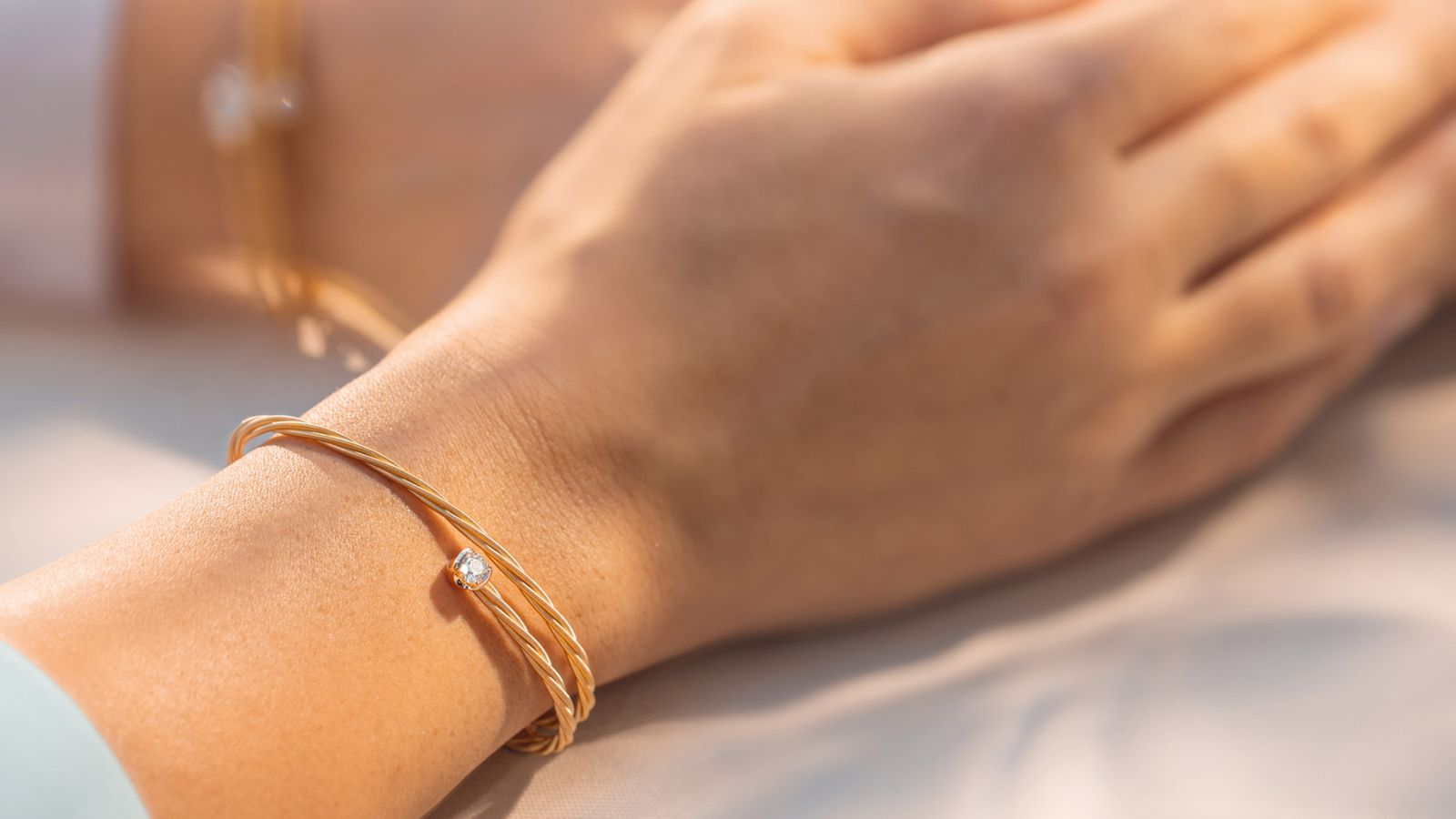 Am Handgelenk strahlt das Armband UMARME MICH – Power of solitaire aus 18 Karat Gelbgold. Die moderne Solitärfassung hält den Viertelkaräter und bietet Raum für eine persönliche Gravur.