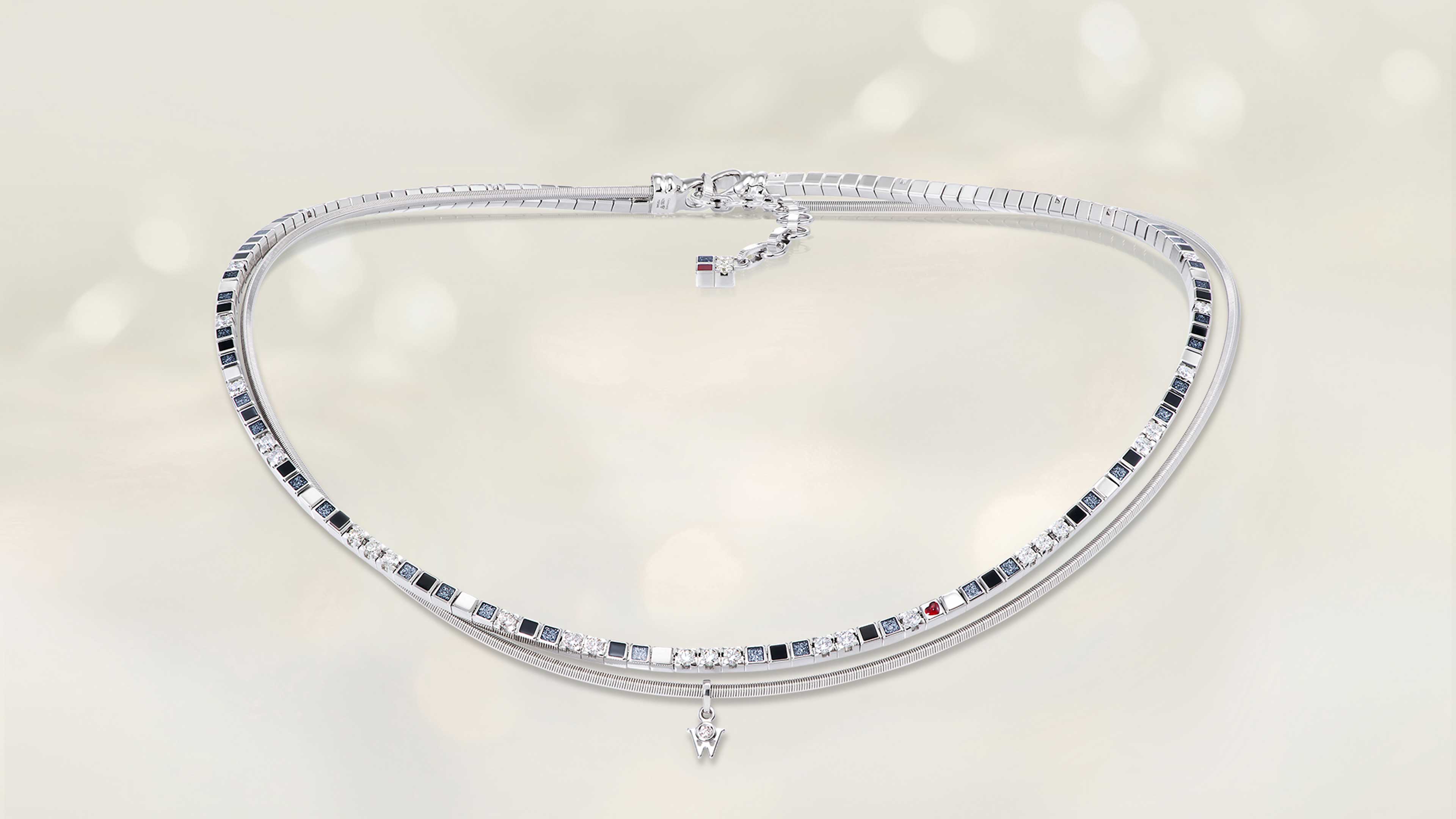 Das Collier POWER IN BLACK aus 18 Karat Weißgold glänzt mit schwarzer Kaltemaille, feinem Sternenstaub und einem kleinen Herz. Collier auf hellem Hintergrund.