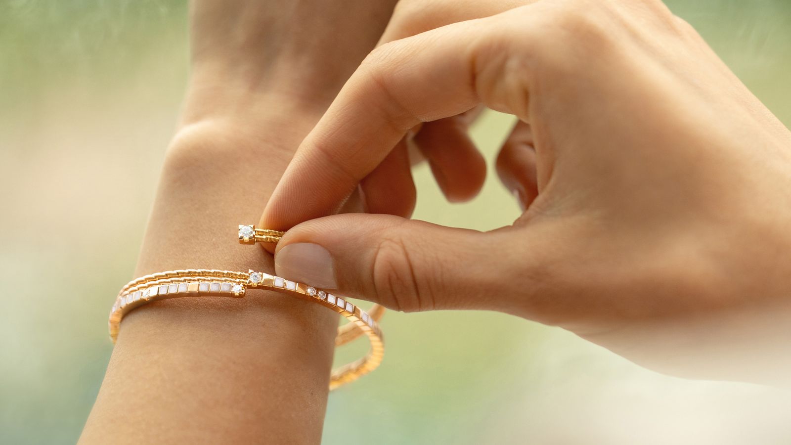 Das 18-karätige Armband Umarme Mich Mein Glück perlmutt am Handgelenk getragen.