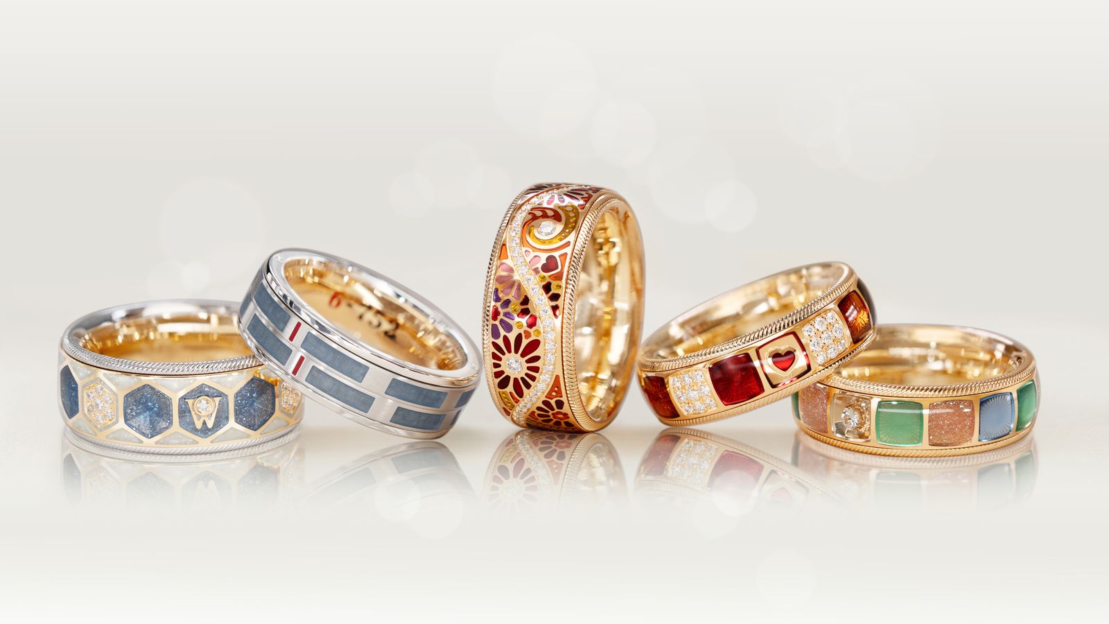 Die fünf Geburtstagsringe von Wellendorff: in 18 Karat Gold, bunter Kaltemaille und handgefassten Brillanten. 5 Ringe auf hellem Hintergrund.