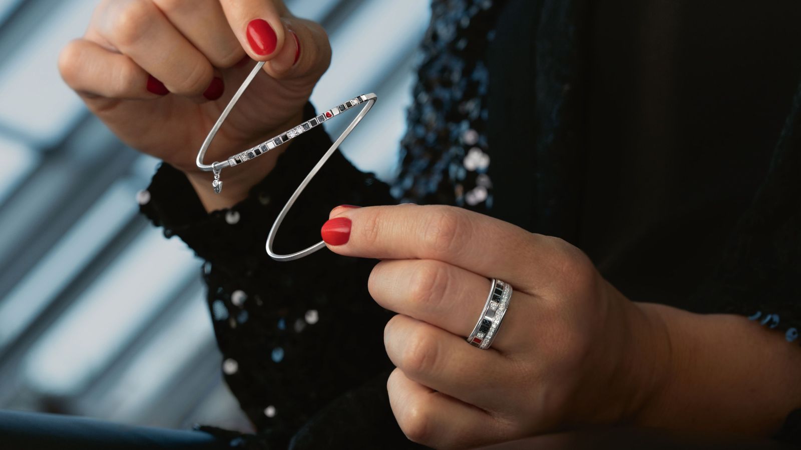 Das Armband POWER IN BLACK aus 18 Karat Weißgold aus schwarzer Kaltemaille mit Sternenstaub, rotes Herz und funkelnde Brillanten auf hellem Hintergrund.