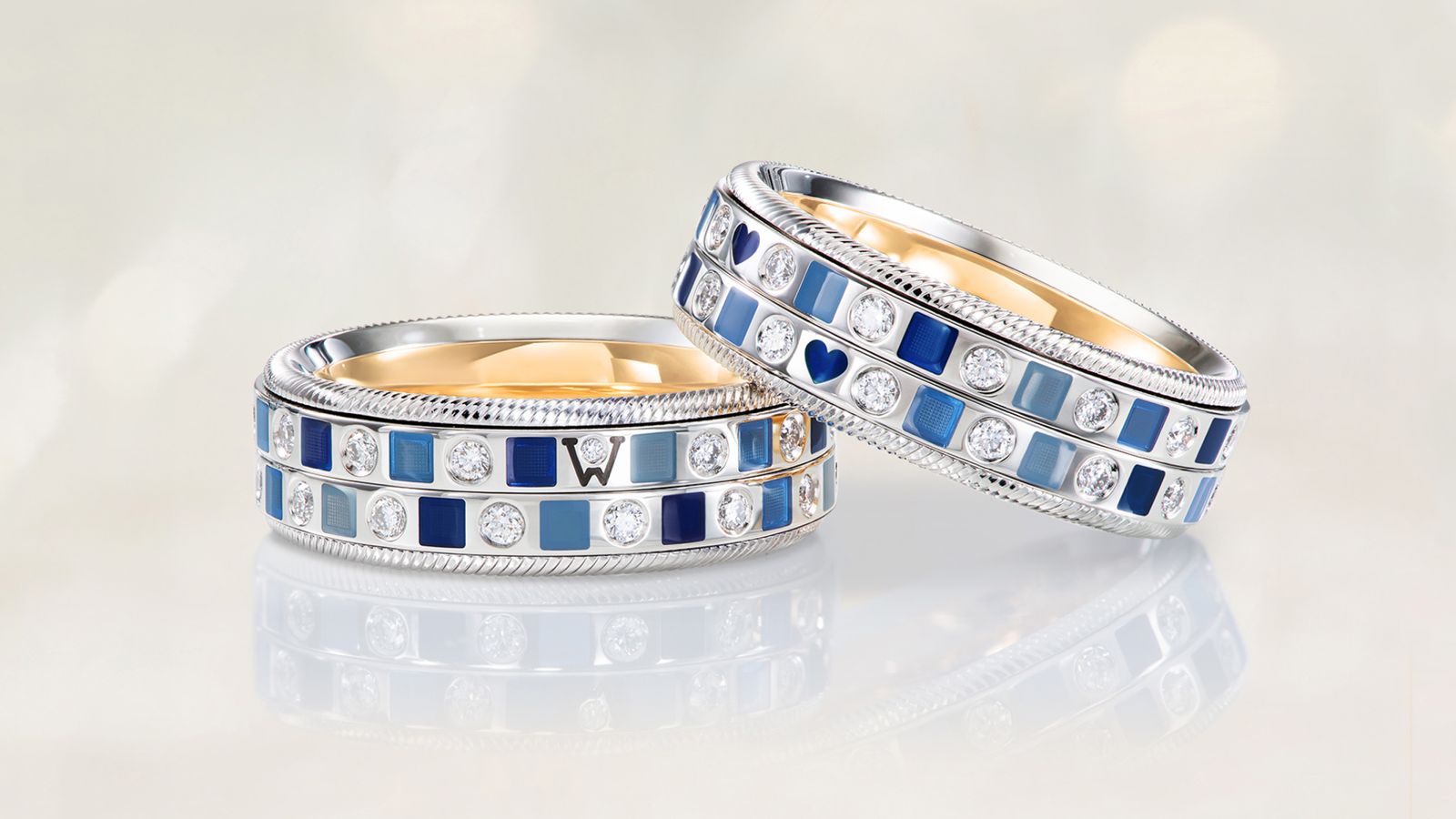 Der drehbare Ring OZEAN Duett aus 18 Karat Gold mit modernen, tiefblauen Mosaiken aus Wellendorff-Kaltemaille und handgefassten Brillanten. Auf grauem Mood Hintergrund.