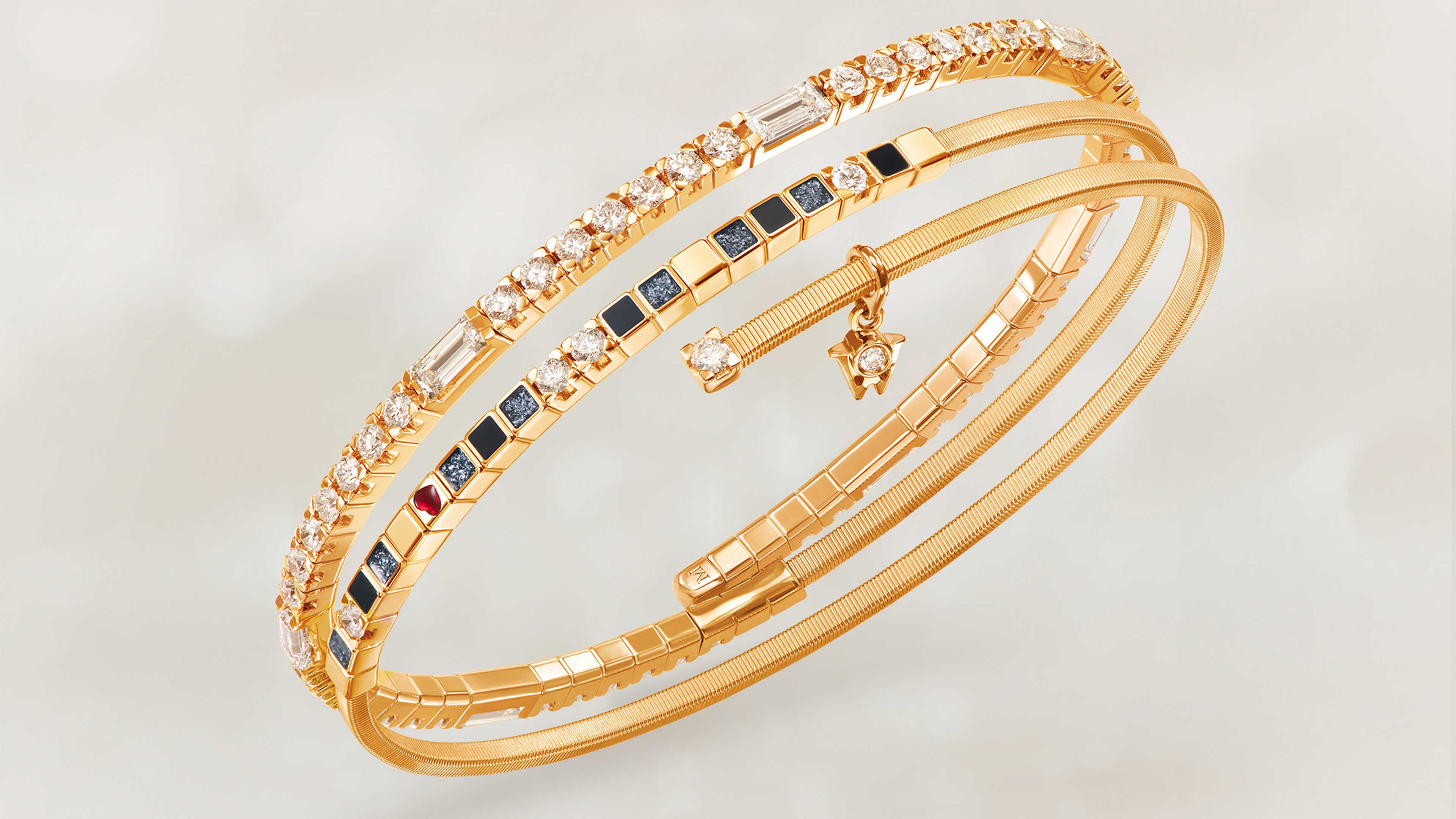 Das Wellendorff Armband UMARME MICH Power in black edel in 18-Karat Gelbgold auf beigem Mood Hintergrund