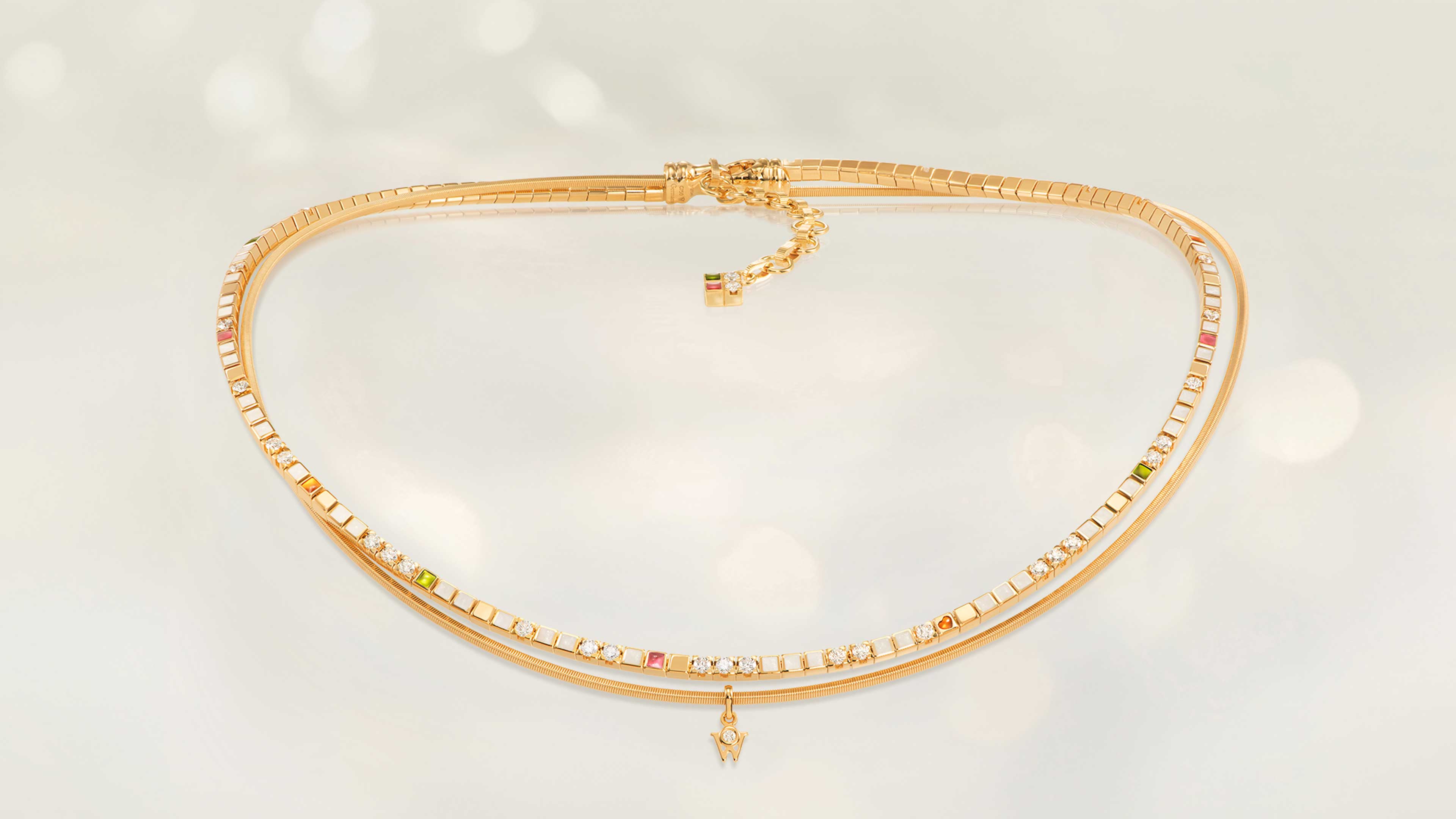 Das Collier POWER IN WHITE aus 18 Karat Gelbgold vereint Perlmuttweiß, Grün, Orange, Rosé, feinen Sternenstaub und ein kleines Herz. Collier auf hellem Hintergrund.