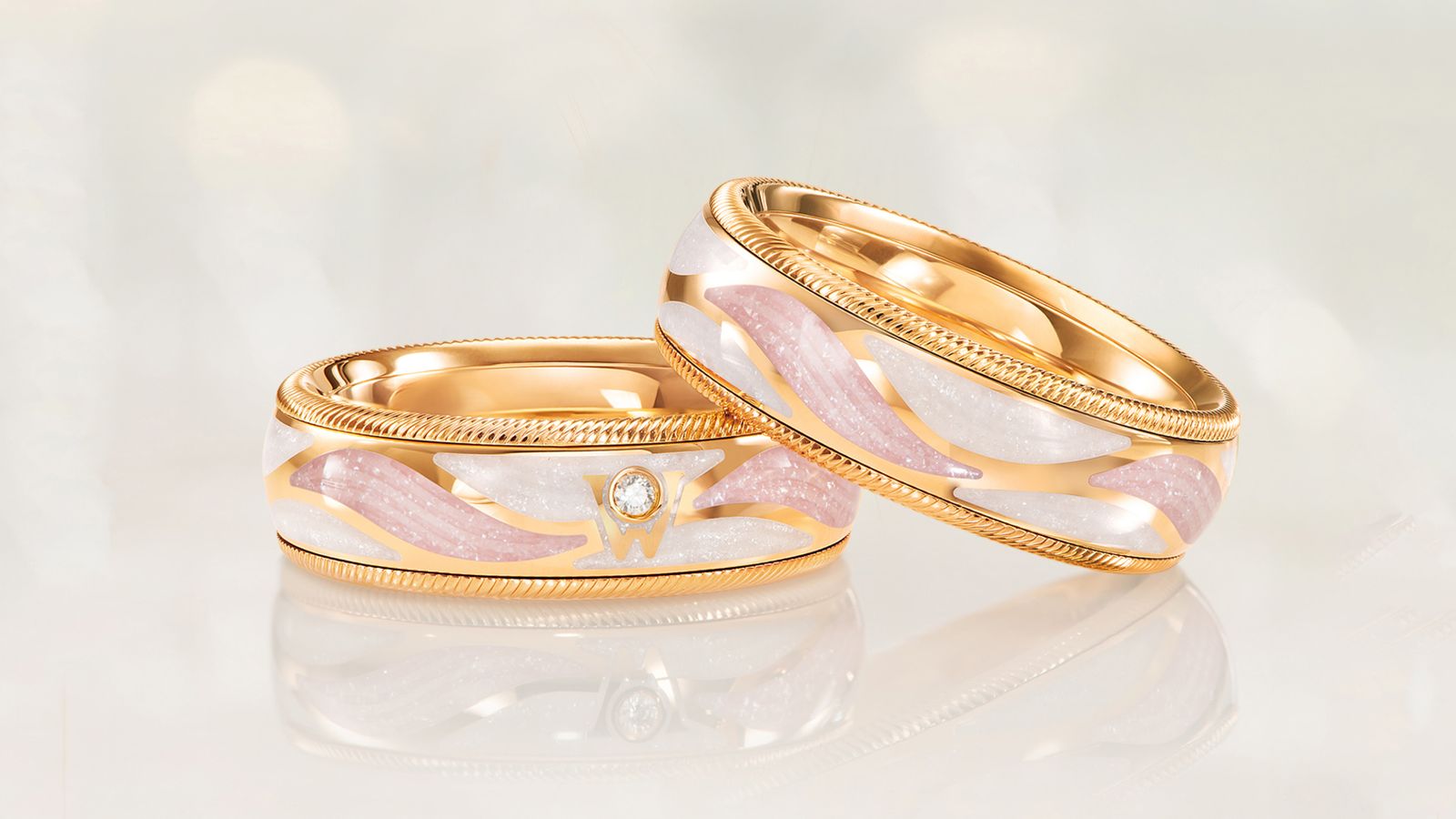 Der drehbare Ring ENGELSSCHIMMER Nude aus 18 Karat Gold mit dynamischen Gravurelementen in zarten Nuancen der Wellendorff-Kaltemaille. Auf grauem Mood Hintergrund.