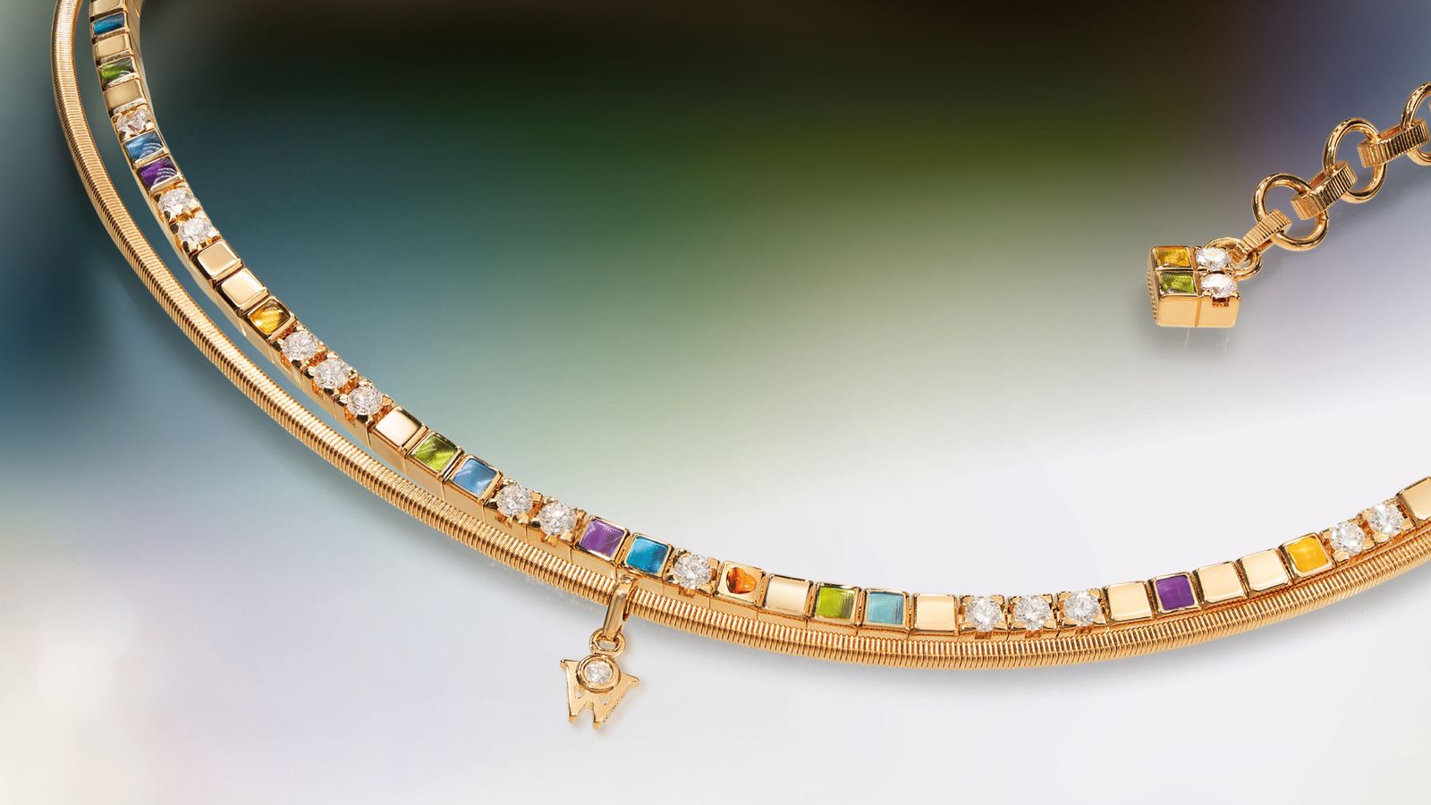 Das Collier POWER IN COLOUR aus 18 Karat Gelbgold begeistert mit Kaltemaille in acht Farben und einem kleinen orangefarbenen Herz. Collier auf hellem Hintergrund.