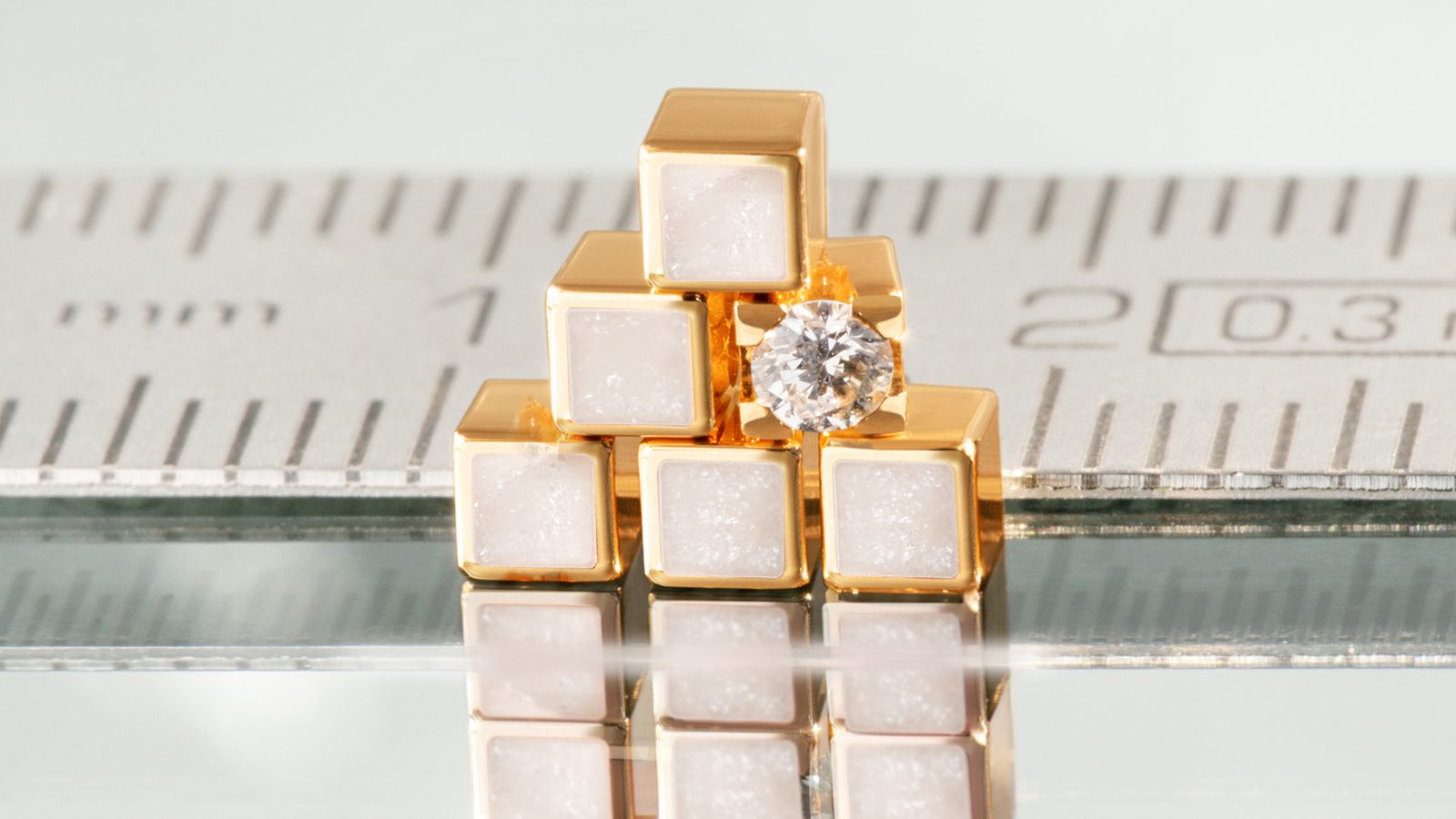 Die magischen Würfel aus 18 Karat Gelbgold und perlmuttfarbener Kaltemaille.